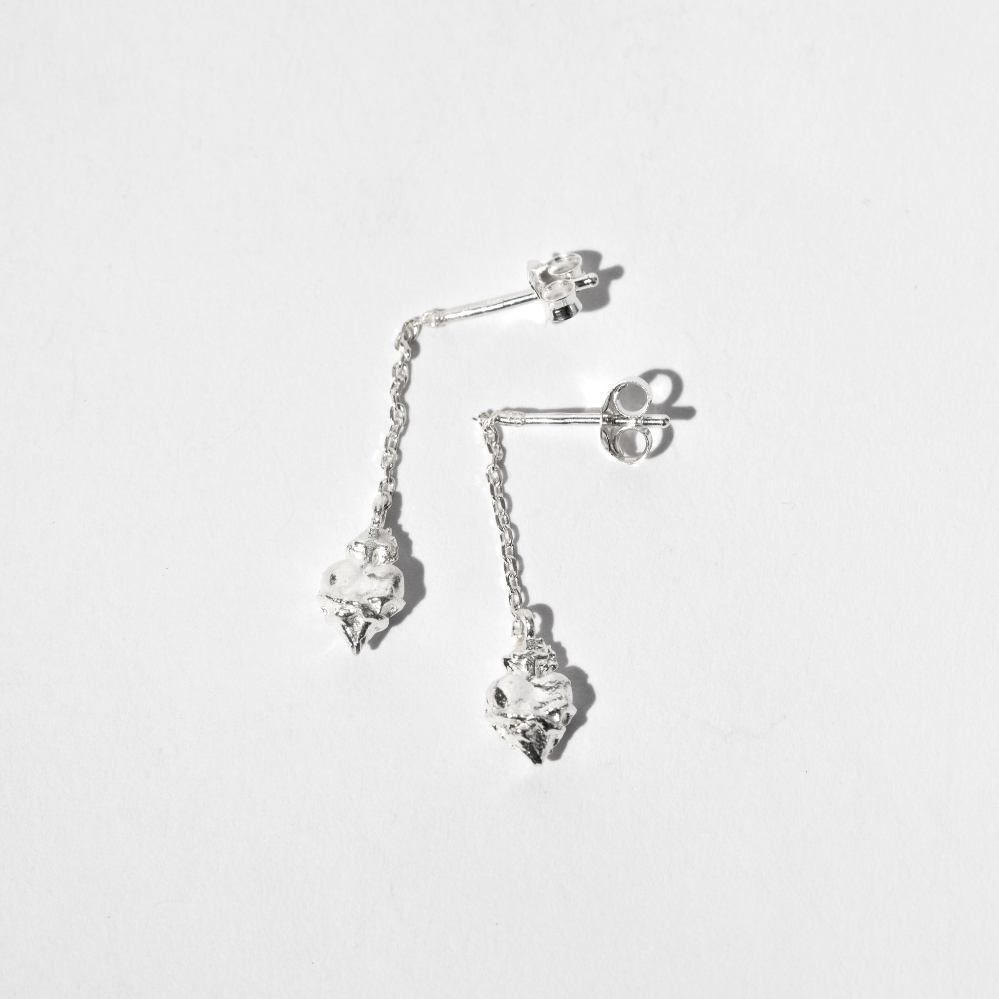A pair of sterling silver scared heart earrings suspended from a sterling silver chain.